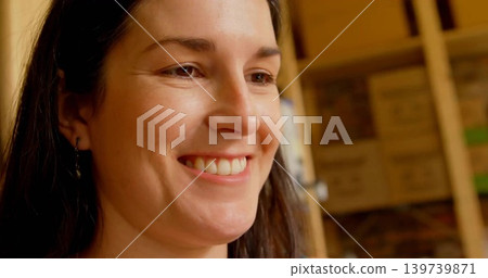 Smiling woman in dark top leaning in storage, showing hoops, wooden shelving, boxes, copy space 139739871