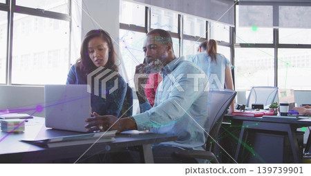Working office team studying laptop screen at modern open-plan office, with red sweater observing 139739901