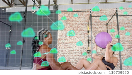Training two women doing partner floor workout at gym in sports bras, holding purple ball, overlay 139739930