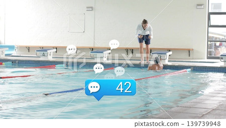 Leaning female coach in hoodie coaching swimmer with cap at community pool, overlays 42, copy space Leaning female coach in hoodie coaching swimmer with cap at community pool, overlays 42, copy space 139739948