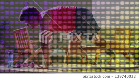 Holding low plank, man in red tank, black shorts on mat in gym, with pink dumbbells Holding low plank, man in red tank, black shorts on mat in gym, with pink dumbbells 139740038