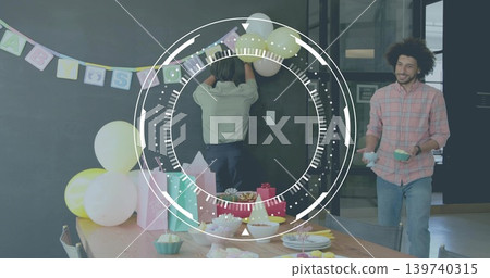 Hanging banner, colleagues in button shirts securing pastel balloons and cupcakes at wooden table Hanging banner, colleagues in button shirts securing pastel balloons and cupcakes at wooden table 139740315