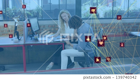 Reviewing two colleagues leaning forward pointing at documents on desk in office, network overlay Reviewing two colleagues leaning forward pointing at documents on desk in office, network overlay 139740342