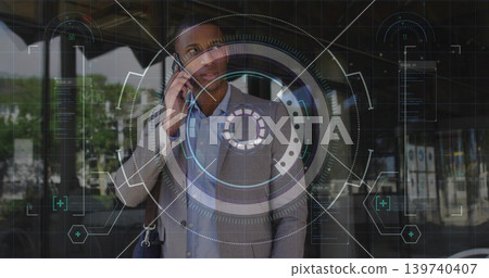 Talking businessman wearing gray blazer and carrying bag, holding phone at glass entrance with HUD Talking businessman wearing gray blazer and carrying bag, holding phone at glass entrance with HUD 139740407