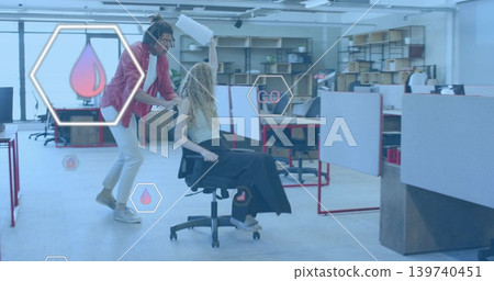 Pushing man in red blazer propelling colleague on rolling chair in office with hex UI graphics Pushing man in red blazer propelling colleague on rolling chair in office with hex UI graphics 139740451