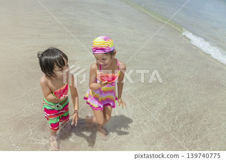 A sister and brother walking along the beach in summer, eating watermelon. A sister and brother walking along the beach in summer, eating watermelon. 139740775