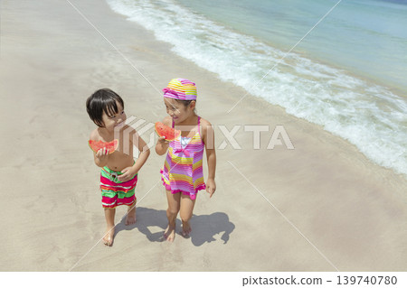 夏天,一對兄妹在海灘邊散步,吃著西瓜。 夏天,一對兄妹在海灘邊散步,吃著西瓜。 139740780