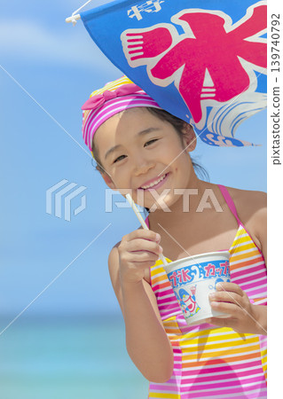 一個女孩在夏日海灘上吃刨冰 一個女孩在夏日海灘上吃刨冰 139740792