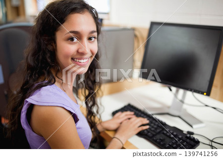 Female teen sitting at lab typing on keyboard, monitor and mouse, wearing lavender top, copy space Female teen sitting at lab typing on keyboard, monitor and mouse, wearing lavender top, copy space 139741256