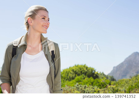 20s woman standing outdoors under pale blue sky, wearing beige backpack near mountain, copy space 20s woman standing outdoors under pale blue sky, wearing beige backpack near mountain, copy space 139741352