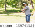 Man in his thirties holding wooden baseball bat, standing in park, wearing trucker cap, copy space 139741384