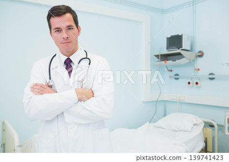 Mid adult male doctor standing in hospital room wearing labcoat, stethoscope, copy space Mid adult male doctor standing in hospital room wearing labcoat, stethoscope, copy space 139741423