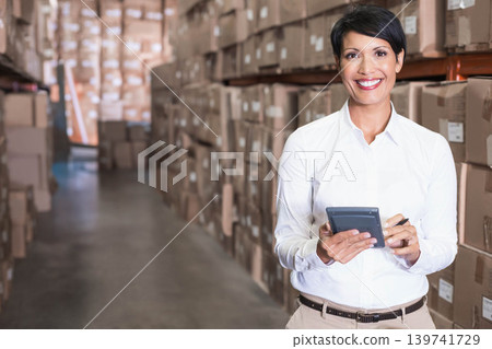 Midlife female in white shirt khaki pants scanning boxes with handheld scanner and pen, copy space Midlife female in white shirt khaki pants scanning boxes with handheld scanner and pen, copy space 139741729