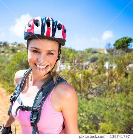 Female cyclist smiling while pausing on sunlit dirt trail wearing helmet and hydration pack Female cyclist smiling while pausing on sunlit dirt trail wearing helmet and hydration pack 139741787