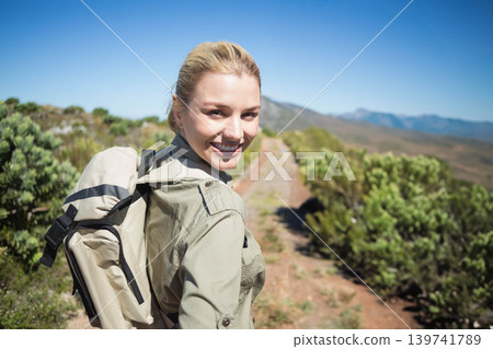 Female hiker walking narrow trail in coastal scrub, wearing khaki shirt, carrying beige backpack Female hiker walking narrow trail in coastal scrub, wearing khaki shirt, carrying beige backpack 139741789