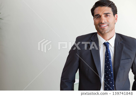 Man in his thirties smiling, posing in office wearing suit jacket navy patterned tie, copy space Man in his thirties smiling, posing in office wearing suit jacket navy patterned tie, copy space 139741848