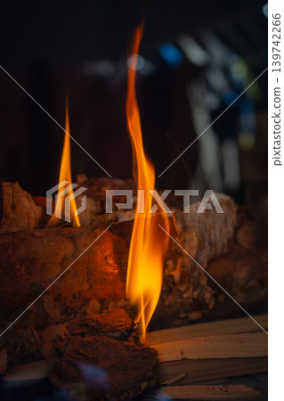 Tall fire extending from wooden log scene. Vertical flame emerging from aged wood with sparks and texture Tall fire extending from wooden log scene. Vertical flame emerging from aged wood with sparks and texture 139742266