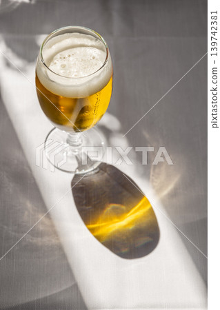 Glass of Cold Beer on a Sunny Restaurant Terrace Table with Long Shadows in Italy Glass of Cold Beer on a Sunny Restaurant Terrace Table with Long Shadows in Italy 139742381