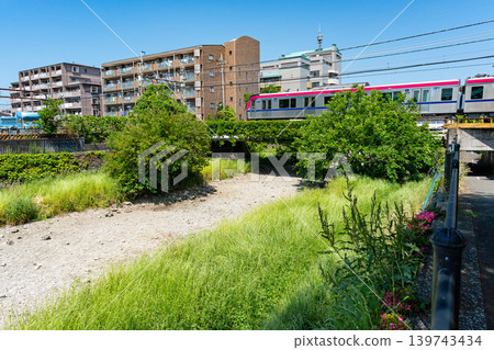 The parched Nogawa River and a Keio Line train in Kikunodai, Chofu City, Tokyo The parched Nogawa River and a Keio Line train in Kikunodai, Chofu City, Tokyo 139743434