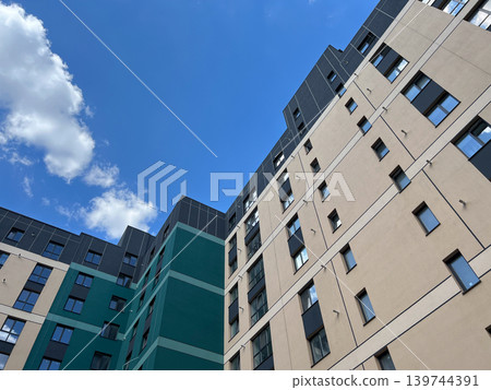 New apartment buildings stand tall against the blue sky, showcasing their unique designs under the bright sun 139744391