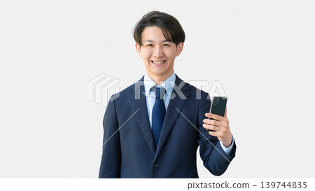 拿著智慧型手機的微笑的男性商人 拿著智慧型手機的微笑的男性商人 139744835
