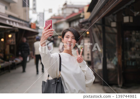 A woman taking a selfie with her smartphone at a tourist spot. A woman taking a selfie with her smartphone at a tourist spot. 139744981