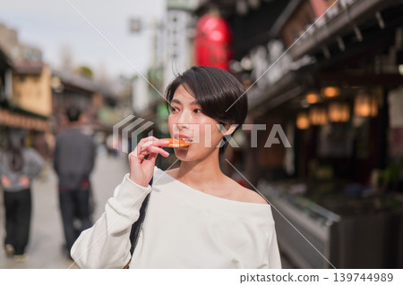 Female tourists enjoying sightseeing while eating rice crackers. Female tourists enjoying sightseeing while eating rice crackers. 139744989