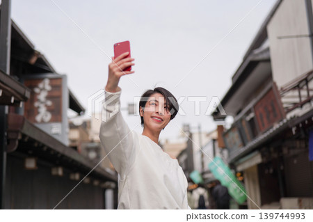 A woman taking photos with her smartphone at a tourist spot. 139744993