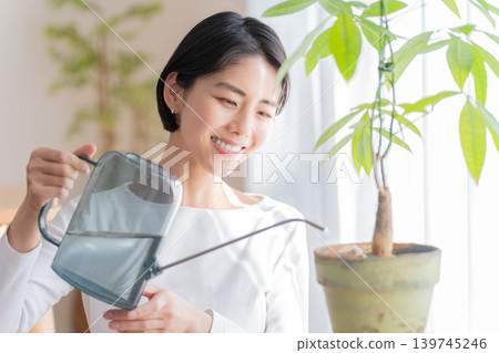 一位女士正在用澆水壺給室內植物澆水。 139745246