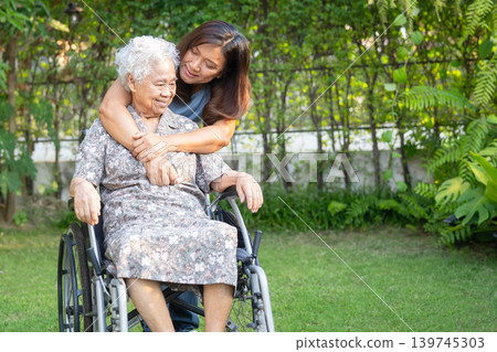 Asian elderly woman disability patient sitting on wheelchair in park. Asian elderly woman disability patient sitting on wheelchair in park. 139745303