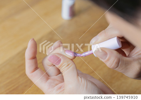 A woman is wearing gel nail polish on the middle finger of her left hand. A woman is wearing gel nail polish on the middle finger of her left hand. 139745910