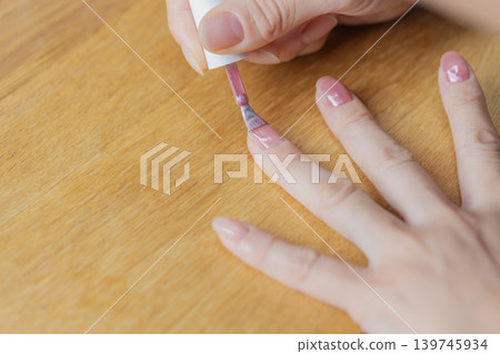 A woman has gel nail polish on the ring finger of her left hand. A woman has gel nail polish on the ring finger of her left hand. 139745934