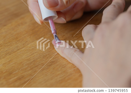 A woman is wearing gel nail polish on the little finger of her left hand. A woman is wearing gel nail polish on the little finger of her left hand. 139745955