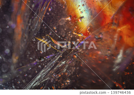 Abstract macro image of colorful refracted light passing through textured glass with droplets, scratch. Modern blurred backdrop, art design, vivid motion, copy space Abstract macro image of colorful refracted light passing through textured glass with droplets, scratch. Modern blurred backdrop, art design, vivid motion, copy space 139746436