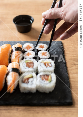 Woman eating sushi with chopsticks Woman eating sushi with chopsticks 139746517