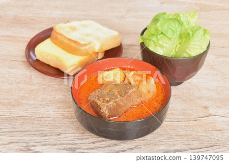 beef curry or Mussamun Indian food with slice potato and tomato on bowl eat couple fresh cos lettuce salad and grilled butter toast bread 139747095