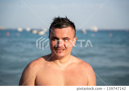 Caucasian man stands in Red Sea water near beach in Sharm El Sheikh Egypt with wet hair and sunny summer daylight. Resort lifestyle and tourism Caucasian man stands in Red Sea water near beach in Sharm El Sheikh Egypt with wet hair and sunny summer daylight. Resort lifestyle and tourism 139747142