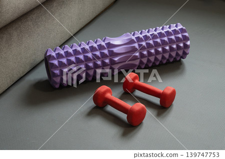 Foam roller and dumbbell on fitness mat 139747753