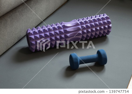 Foam roller and dumbbell on fitness mat Foam roller and dumbbell on fitness mat 139747754