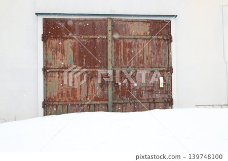 A scene with a rusty door covered in snow. A scene with a rusty door covered in snow. 139748100