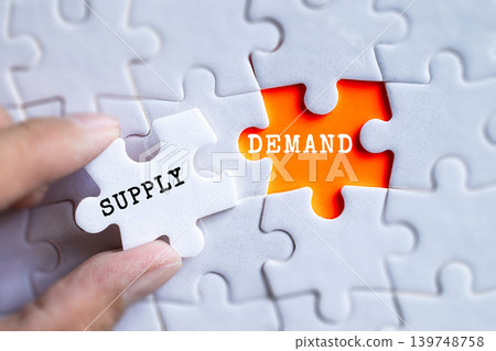 Hand fitting Supply and Demand orange puzzle pieces together on gray jigsaw background, economics and market balance concept Hand fitting Supply and Demand orange puzzle pieces together on gray jigsaw background, economics and market balance concept 139748758