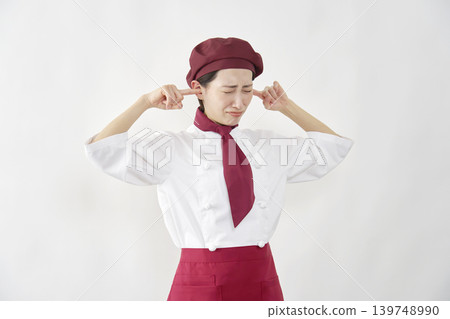 Female pastry chef/baker/cafe employee covering her ears against a white background. 139748990