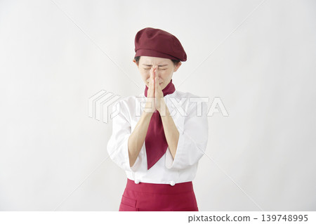 Female pastry chef/baker/cafe employee pleading against a white background. Female pastry chef/baker/cafe employee pleading against a white background. 139748995