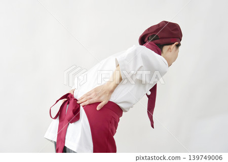 Female pastry chef/bakery/cafe employee; suffers from lower back pain; white background. Female pastry chef/bakery/cafe employee; suffers from lower back pain; white background. 139749006