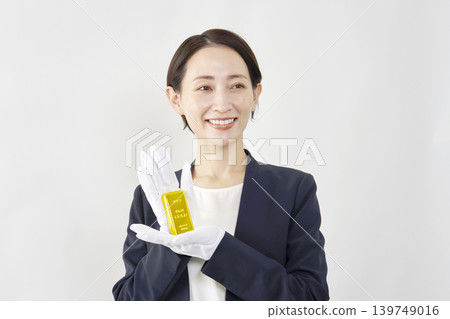 女性鑑定師手持金條，白色背景 139749016