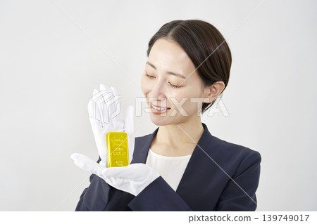 Female appraiser holding a gold bar, white background Female appraiser holding a gold bar, white background 139749017
