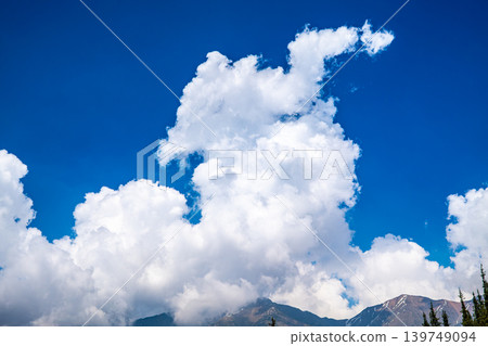 Dramatic white cumulus clouds over snow capped Tian Shan mountains and blue sky 139749094