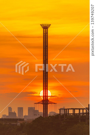 Towering amusement ride silhouette against a vibrant sunset sky Towering amusement ride silhouette against a vibrant sunset sky 139749207