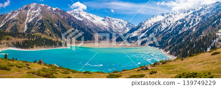Spectacular wide panoramic view of turquoise Big Almaty Lake surrounded by snow capped Tian Shan mountains Kazakhstan Spectacular wide panoramic view of turquoise Big Almaty Lake surrounded by snow capped Tian Shan mountains Kazakhstan 139749229