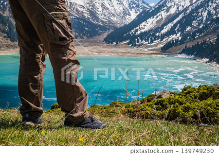Hiker standing at edge of turquoise Big Almaty Lake Hiker standing at edge of turquoise Big Almaty Lake 139749230